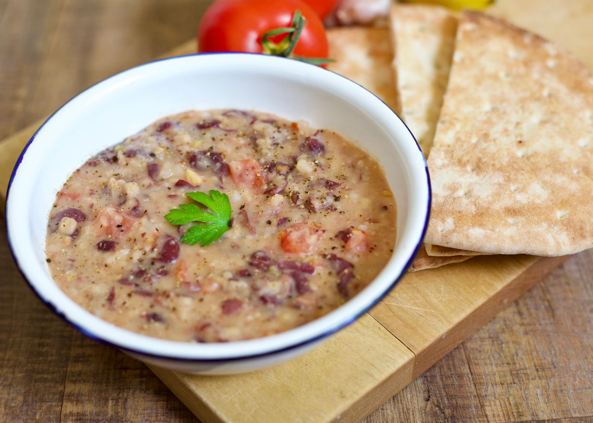 Image of a bowl of stewed beans with pita wedges and a fresh tomato